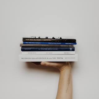 Hand holding up a stack of books