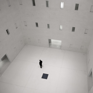 Lone figure in empty room with windows